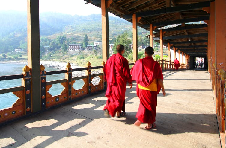 Two Buddhist monks walking over a bridge