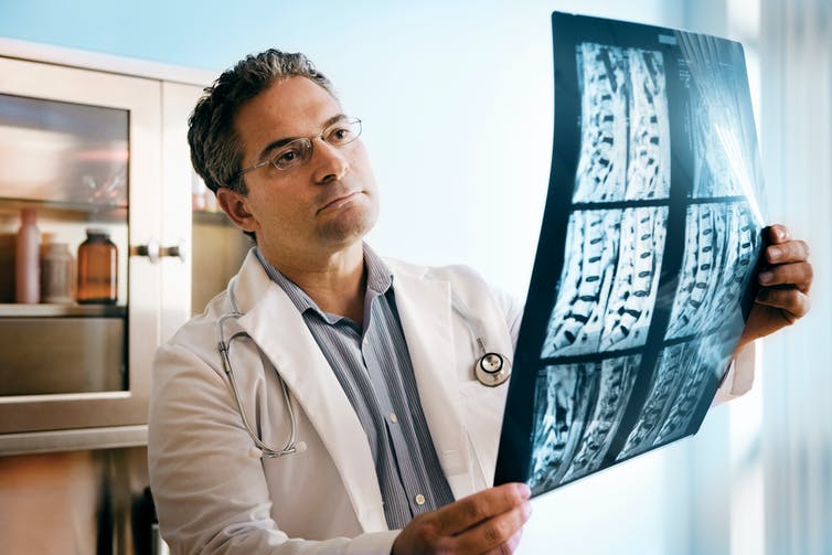 A doctor looks at an MRI of a spinal cord.