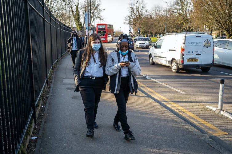 Two girls in masks leaving school