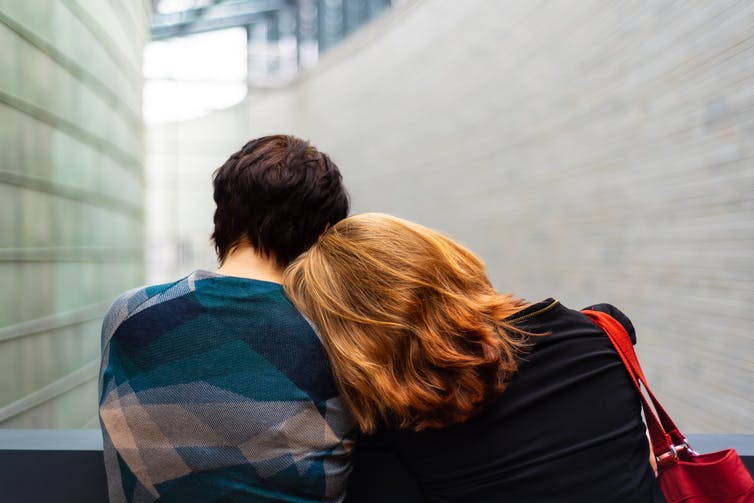 A woman rests her head on someone's sholder.