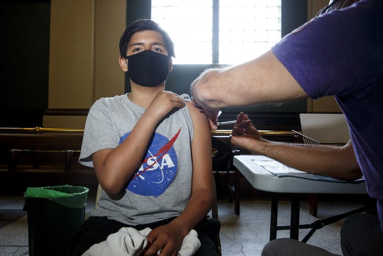 A boy wearing a face mask getting an injection