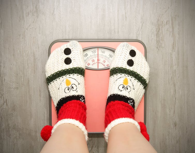 Person in festive socks standing on a bathroom scale.