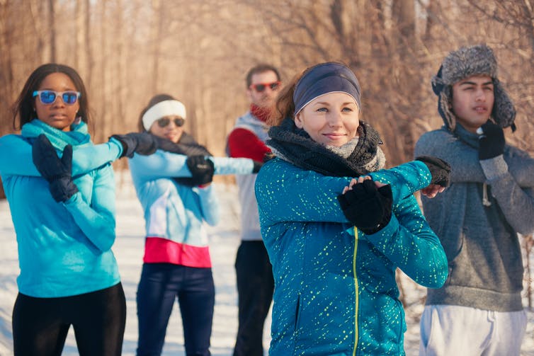 A group of people in winter athletic gear stretch