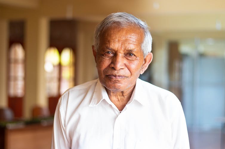 Portrait of an older South Asian man wearing an off-white shirt