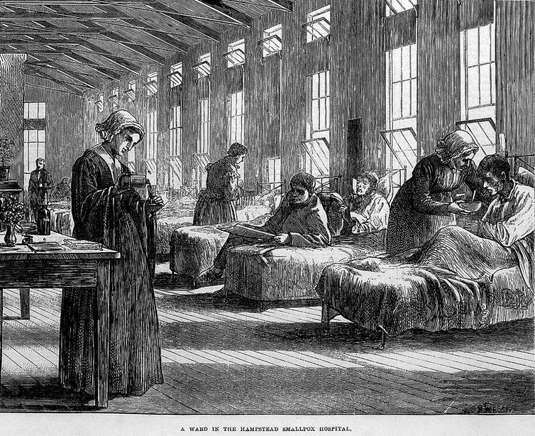 Old illustration of a large room with a row of patients in beds and nurses looking after them