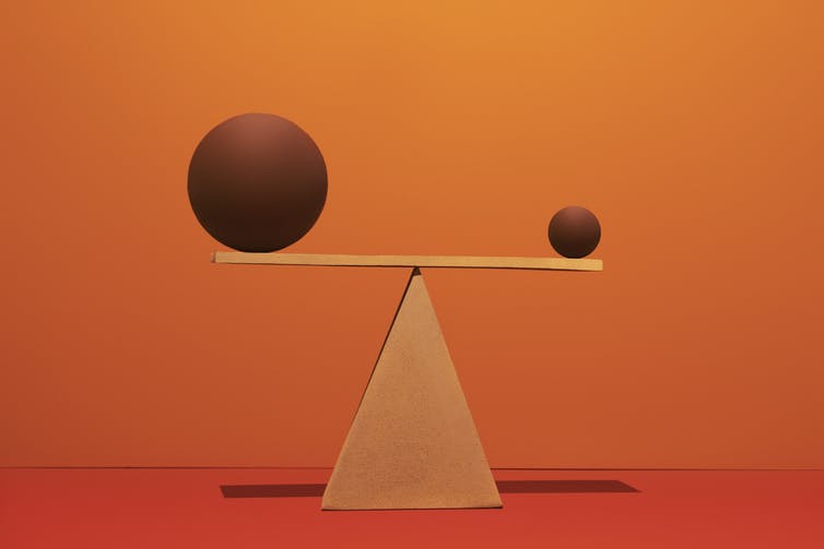 A balance with a large ball on one side and a small ball on the other side.