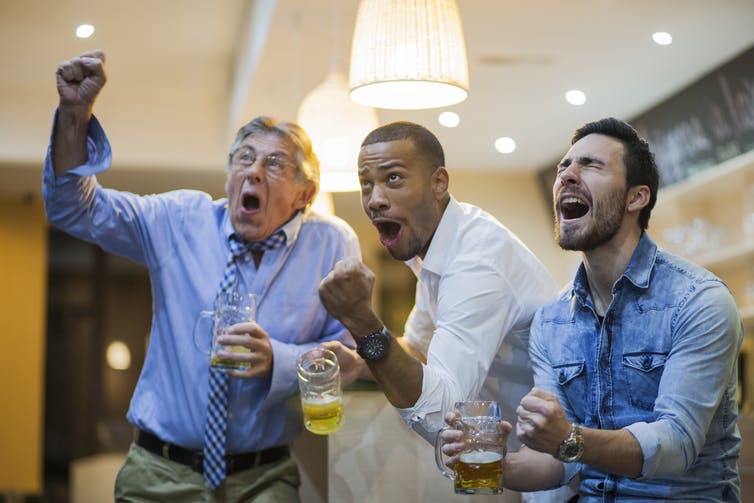 Three men watching sports and drinking.
