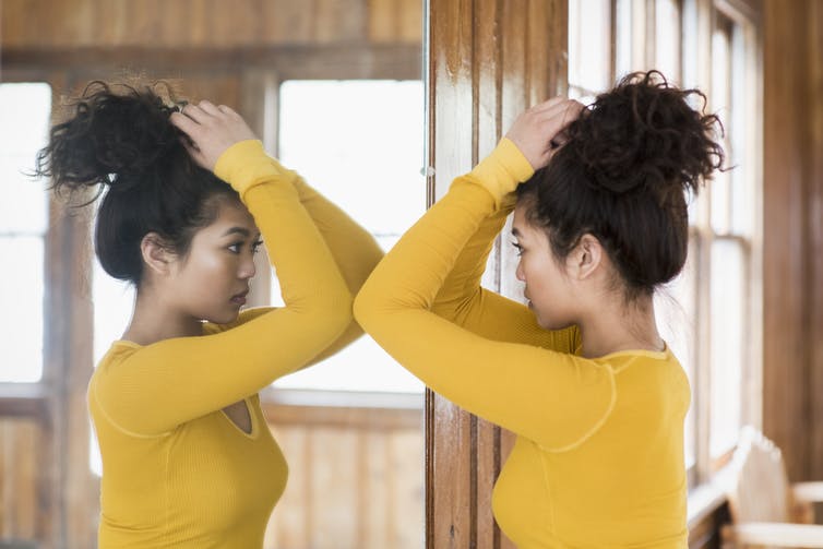 A woman looking at herself in a mirror.