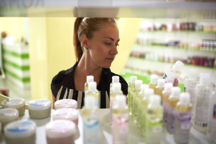 A woman looks at the selection of skincare products on a store shelf.