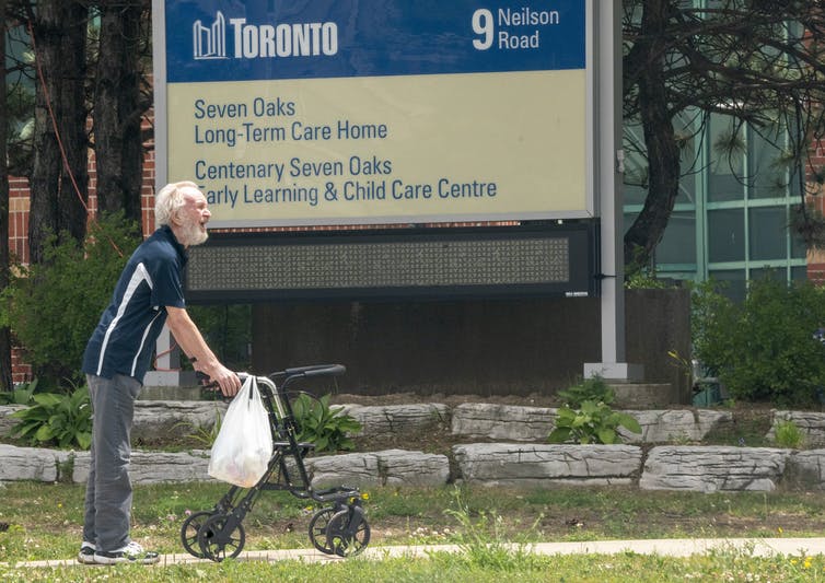 A man pushes his walker as he strolls outside a long-term care home.