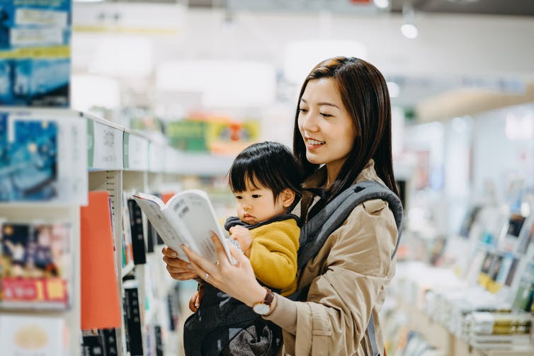 woman in bookstore with toddler in baby carrier