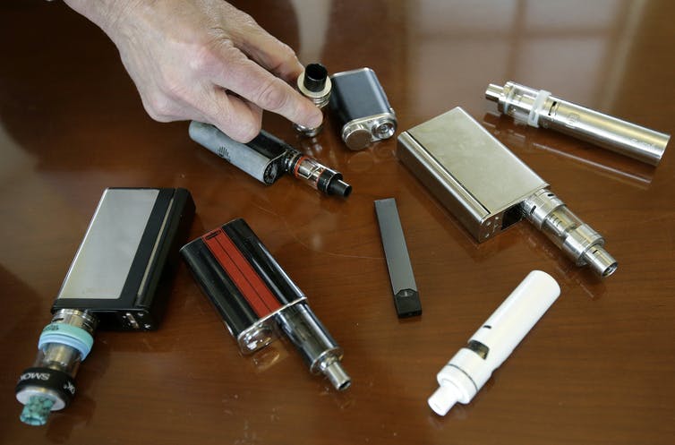 Numerous types of vapes on a desk.
