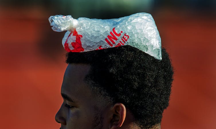 A young man with a bag of ice on his head.