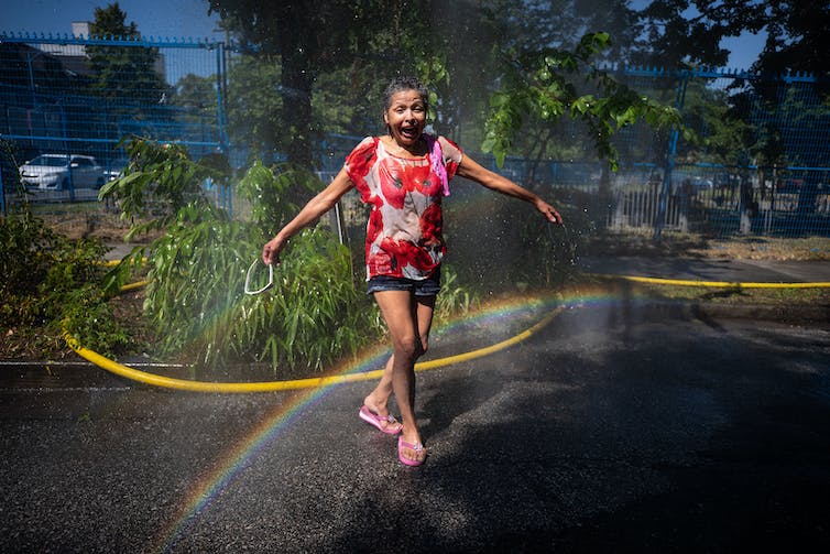 A woman cools off in the water at a temporary misting station