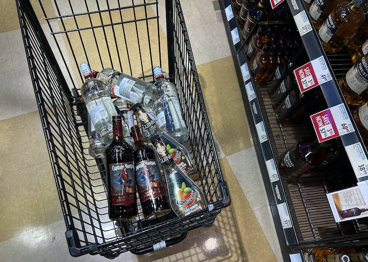 A shopping cart with several bottles of liquor in it