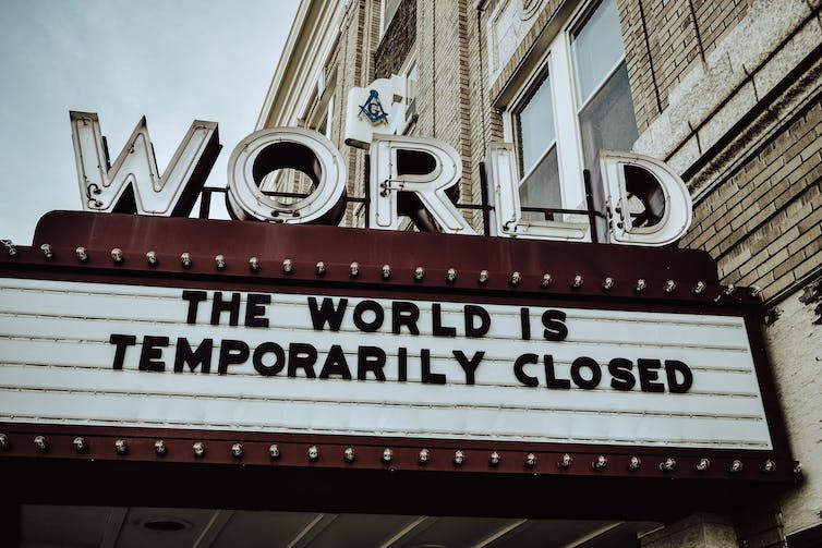 a cinema marquee with the sign THE WORLD IS TEMPORARILY CLOSED