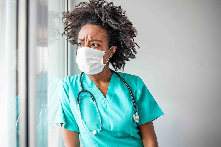 A female healthcare worker looks out the window.