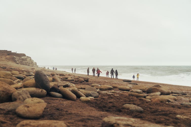People walking along a rocky beach at Bridport