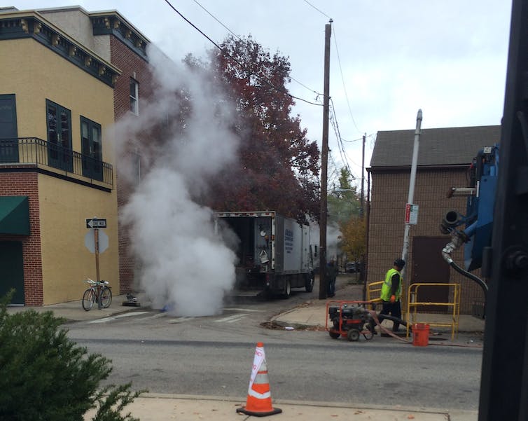 Steam and gases rise out of a sewer manhole.