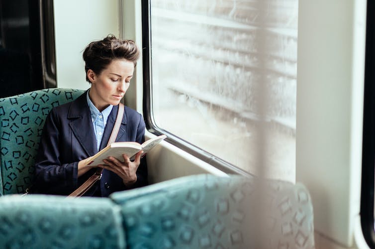 Businesswoman reading a book while traveling on a commuter train