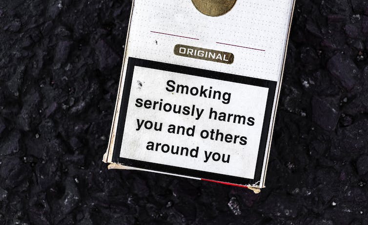 A plain pack of cigarettes with a health warning label.