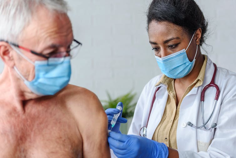 A senior man receives a vaccination.