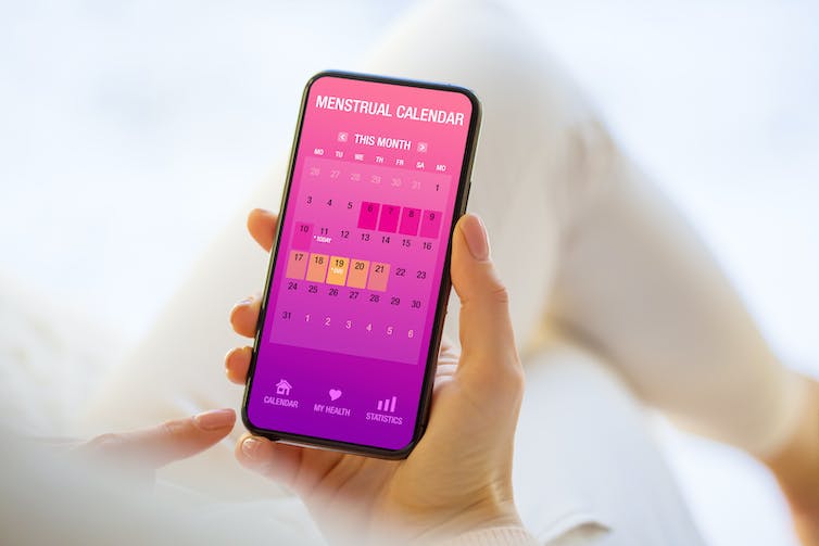 A woman uses a menstrual calendar on her phone to track stages of her cycle.