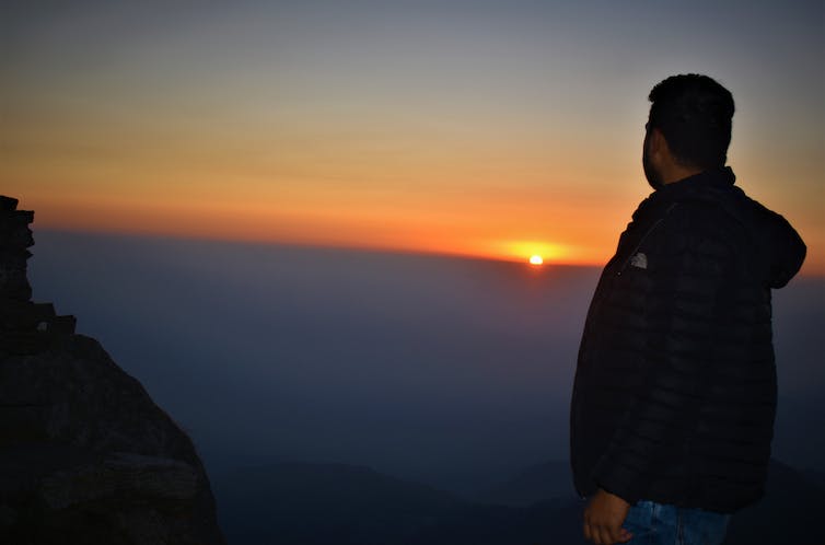 a man watches the sun set on the horizon