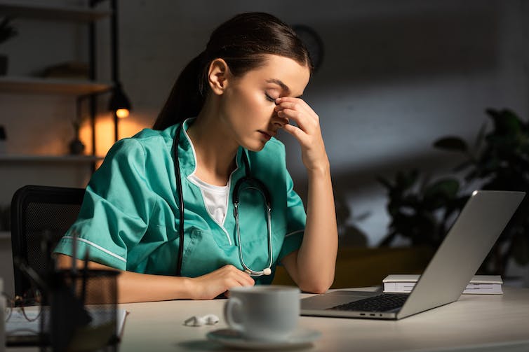 A nurse sitting at a desk during a night shift.