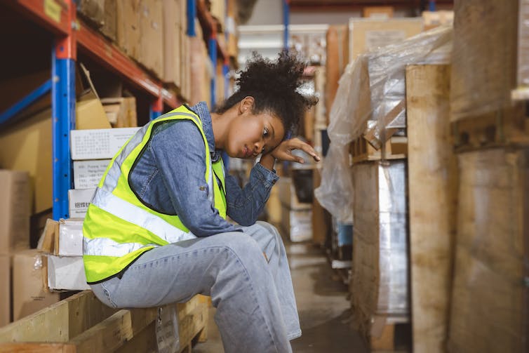 A young woman working in a warehouse takes a break.
