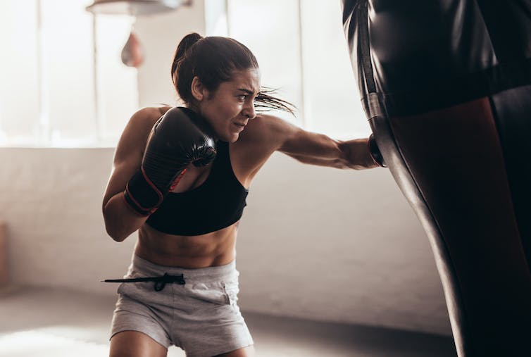 Female boxer hitting a huge punching bag at a boxing studio