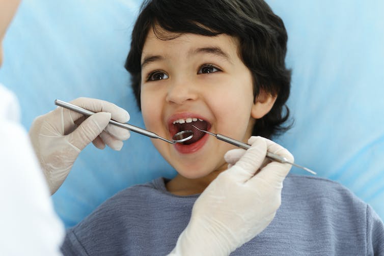 A boy being examined. by a dental care worker out of shot