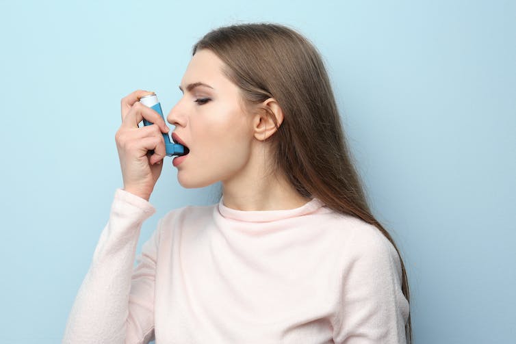 Woman holding asthma pump to her mouth
