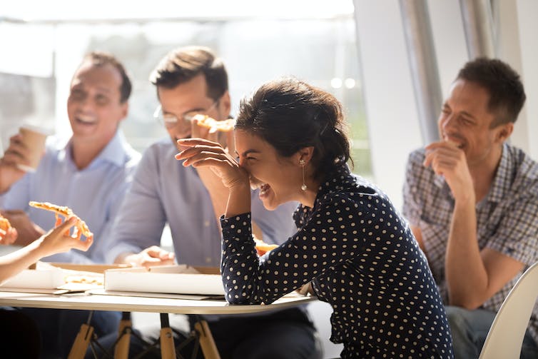 A group of business people laugh around a table.