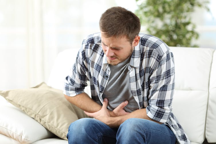 A man holds his stomach in pain.