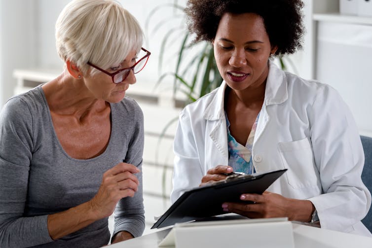 A woman with gray hair consulting with a doctor