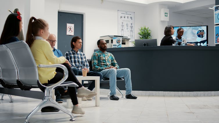 Several people sitting in the waiting room of a medical clinic