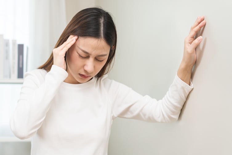 A woman holds her ear in pain.