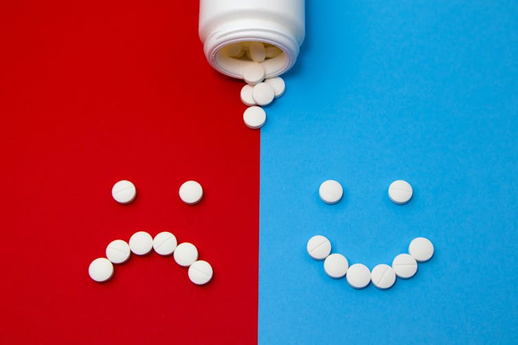 White pills forming a sad face against a red background on the left, and white pills forming a happy face against a blue background on the right