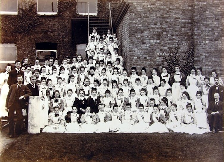 Group photograph of uniformed nurses in Maidstone, with buildings behind them.