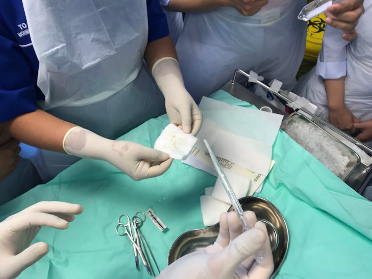 A medical team's hands, handling medical equipment.