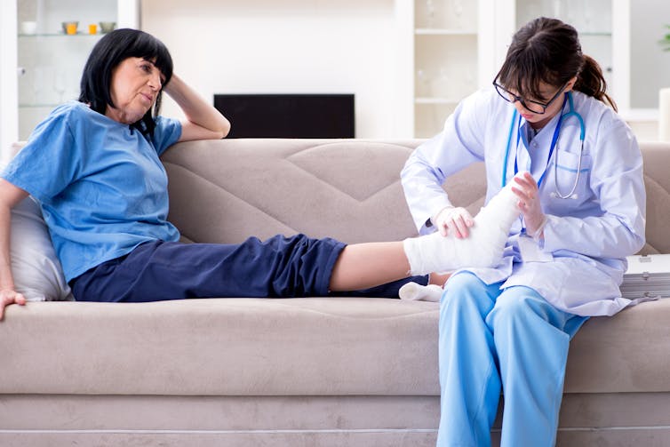 A doctor examines an older female patient's fracture ankle.