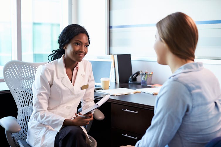 A woman conferring with a doctor in a white coat