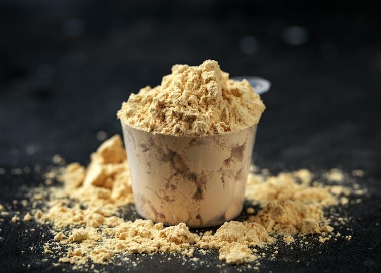 A scoop of protein powder on a black background