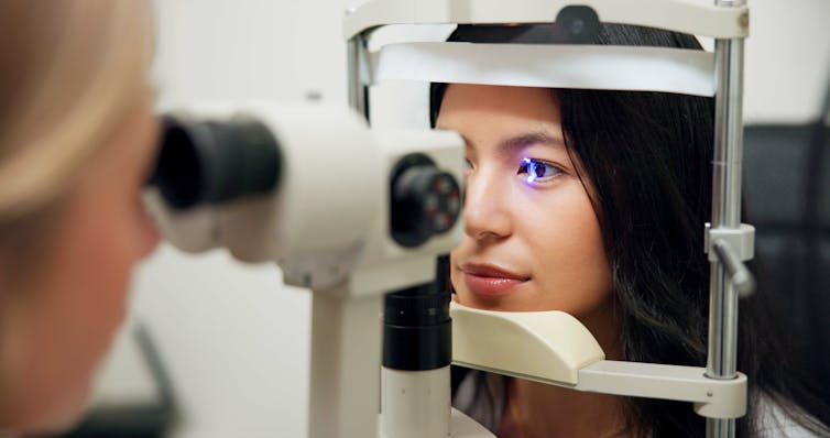 Machine shines light into a woman's eye during an eye exam.