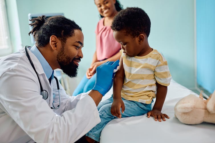 A doctor giving a young boy a needle.