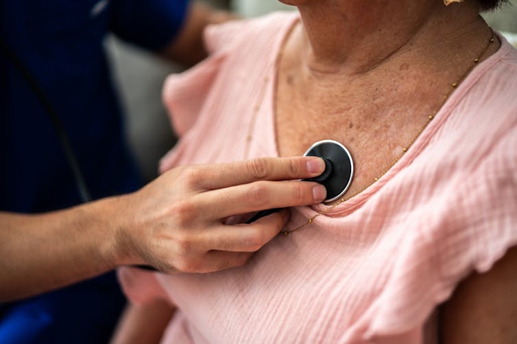 Clinician holding stethoscope against a patient's chest