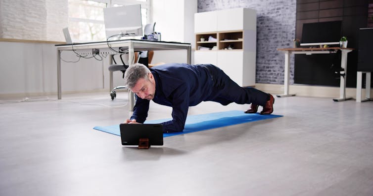 A man performs a plank in his office.