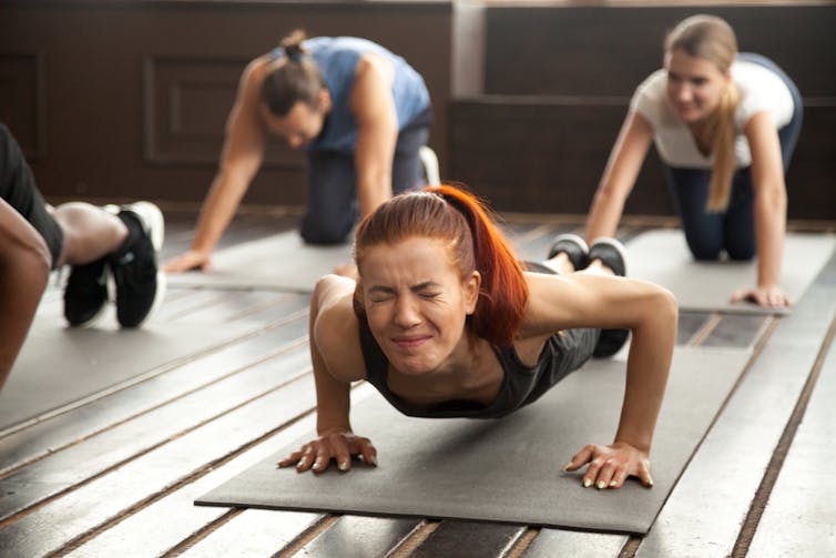 A woman grimaces as she does a push up.