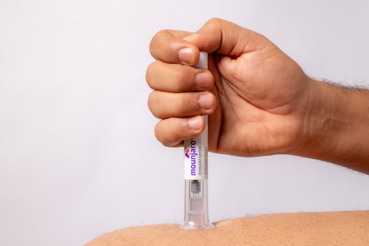 A person injects a weight loss jab into their thigh.